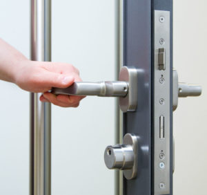 En hånd som åpner en dør med adgangskontrollsystem