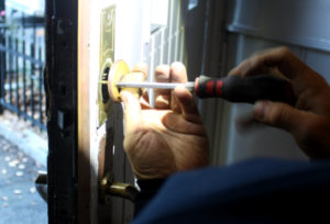En låsesmed som installerer en ny lås med lys fra en hodelykt