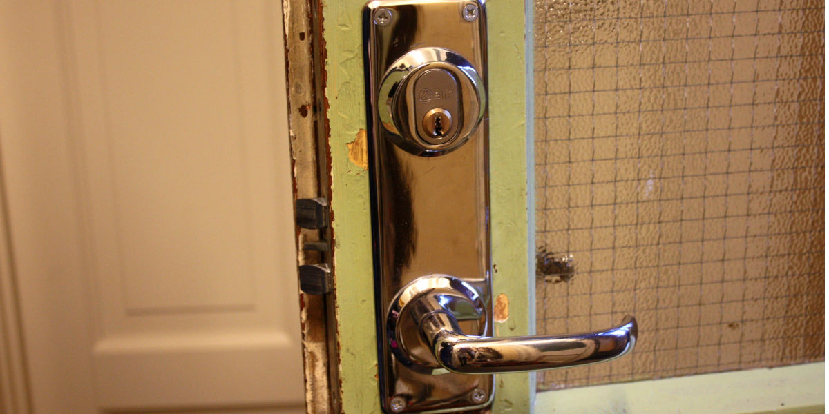 En grønn glassdør med lås og dørhåndtak