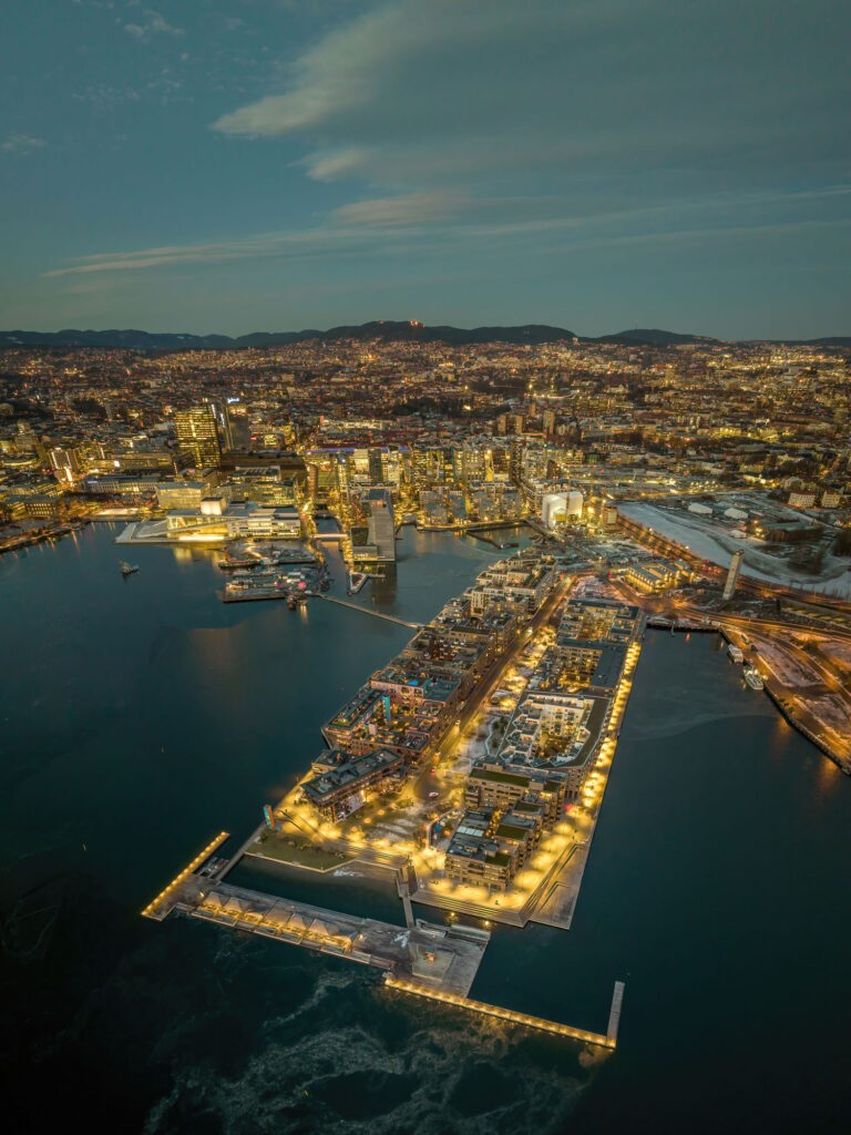 Aerial shot of Oslo at sunset, with lots of buildings and lights, surrounded by sea, Norway